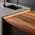 Modern kitchen island showcasing precision zoning with distinct wet and dry prep micro-regions defined by contrasting quartz and timber countertops, illuminated by subtle under-counter lighting.
