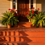 A beautifully designed home entryway featuring a porch painted in a warm terracotta hue, creating a hospitable and inviting first impression under golden hour light.
