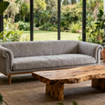 A peaceful biophilic living room with a linen sofa, wooden coffee table, and lush indoor plants, bathed in natural light from large windows showing a garden view.