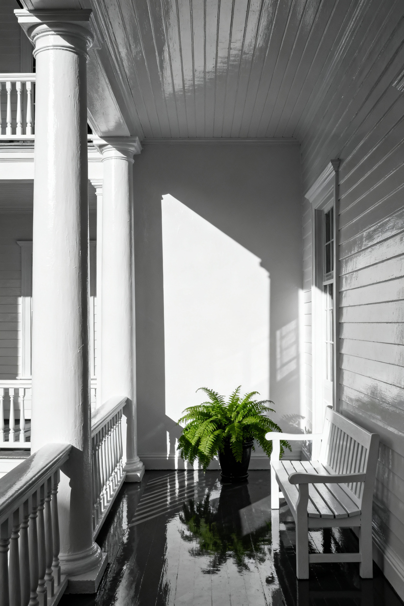 A deeply shaded residential portico painted in brilliant high-gloss white, showing how the reflective sheen amplifies limited natural light and brightens the seating area.