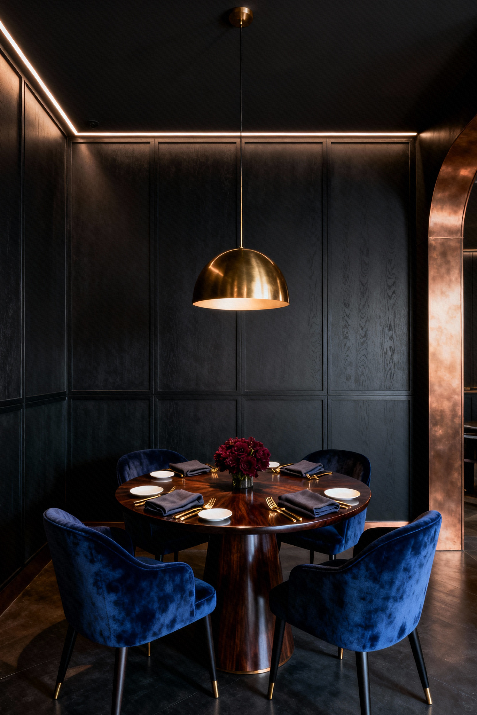 A wide shot of a luxurious, intimate small dining room for four, featuring a round walnut table, sapphire velvet chairs, and warm, dramatic lighting.