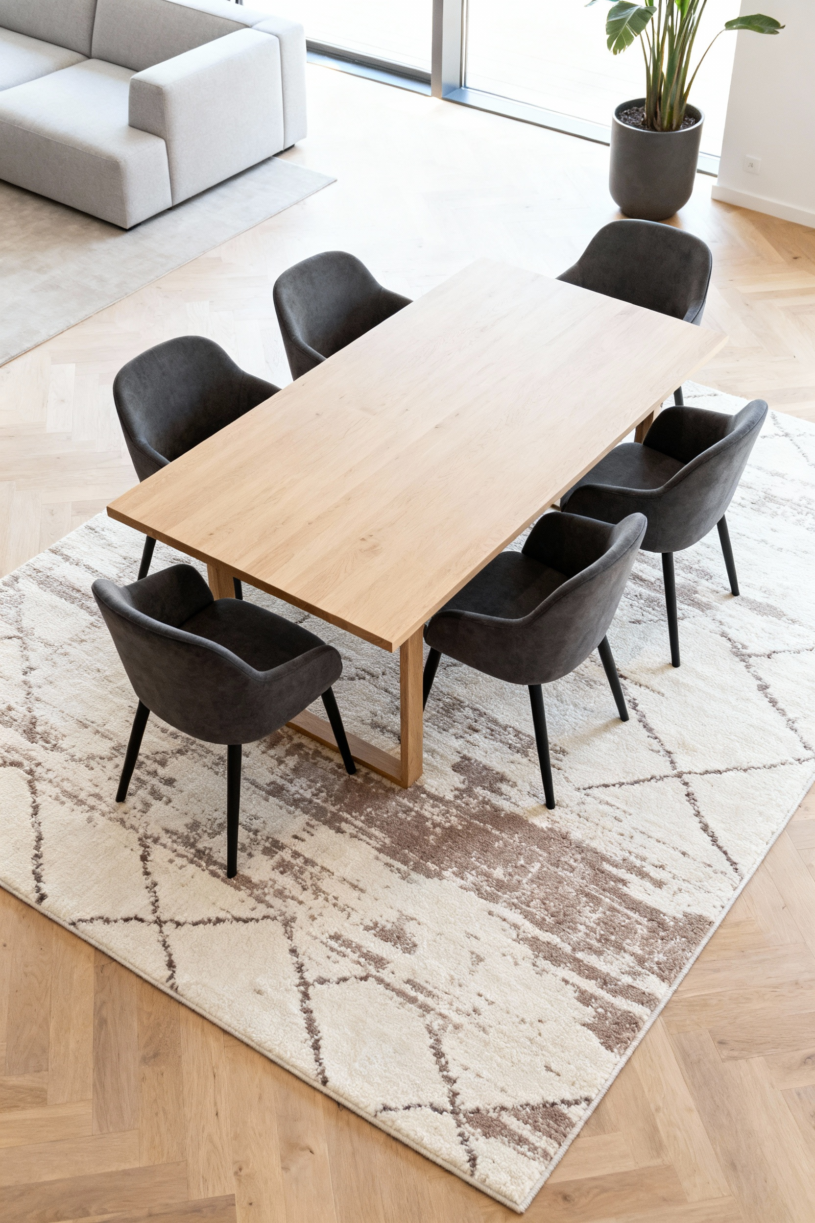 A photograph illustrating the 24-inch rug clearance rule in an open-concept dining room, showing a large rug extending past all pulled-out dining chairs in a modern, naturally lit space.