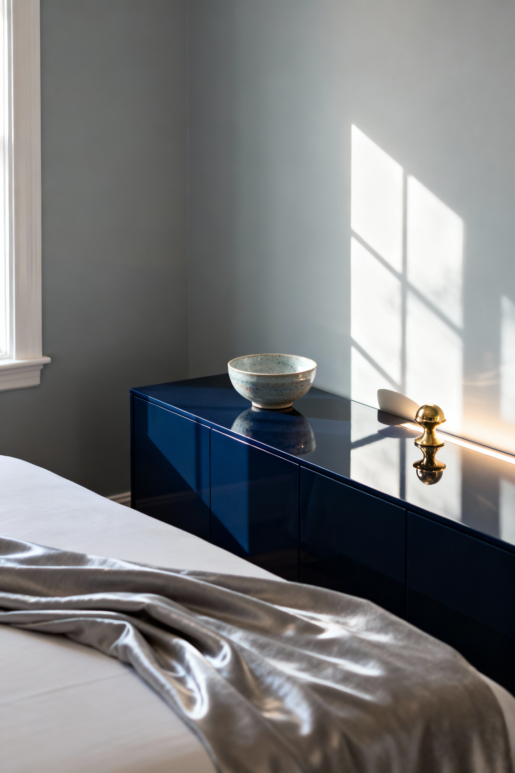 Serene small bedroom with a lacquered credenza, polished brass decor, and a satin-finish wall subtly reflecting natural light to enhance spaciousness.