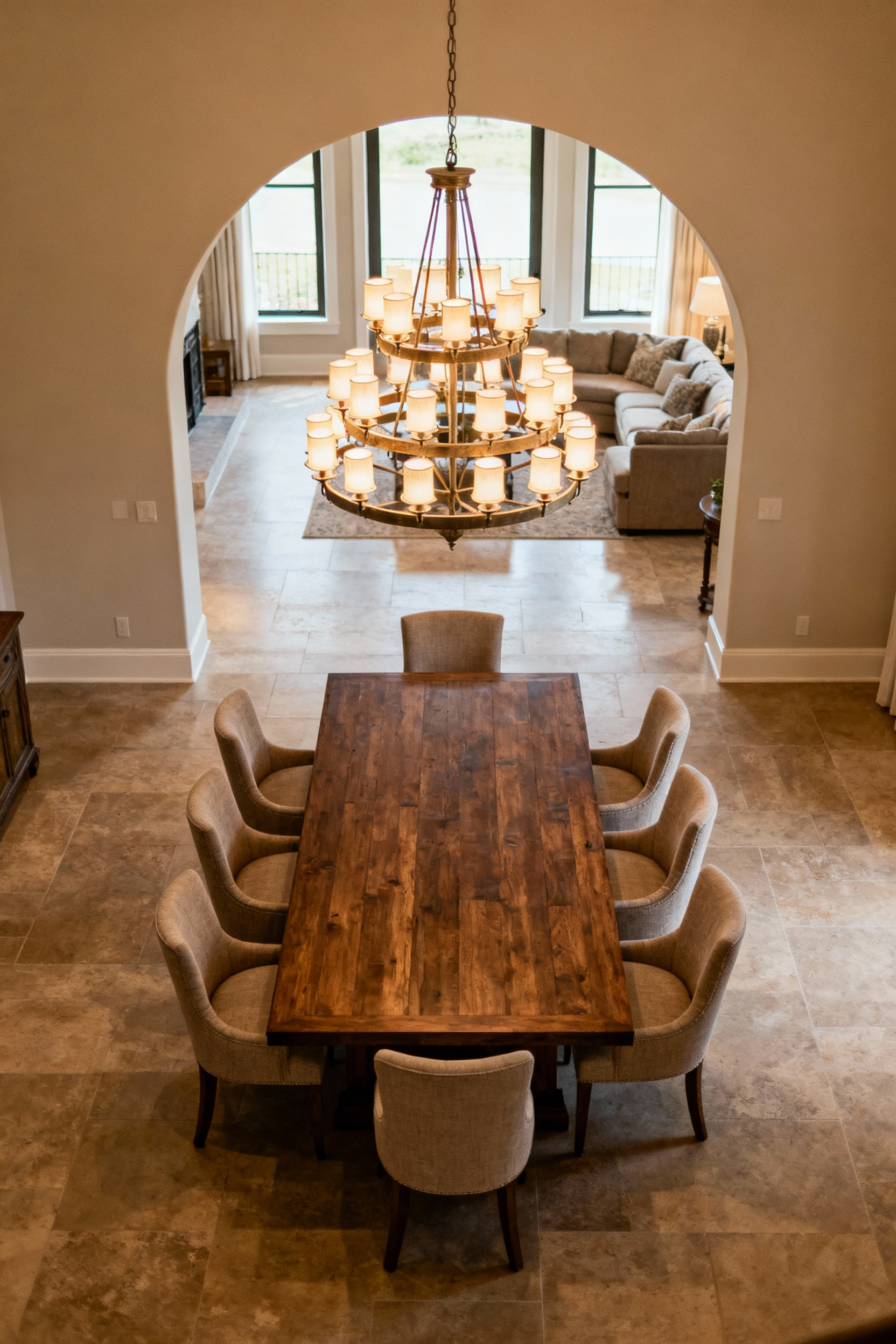 Strategically placed dining room with large wooden table, upholstered chairs, and a grand chandelier, emphasizing communal interaction and connection.