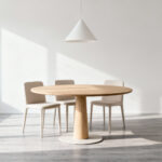 Small, brightly lit dining room featuring a round oak pedestal table and four fully tucked-in minimalist chairs, emphasizing space-saving design and fluid movement.