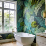 A bright, modern bathroom featuring green botanical wallpaper with fern patterns and a white soaking tub.