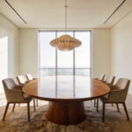 A modern dining room with an oval table and acoustic wood wall panels designed for mindful space planning and noise reduction.