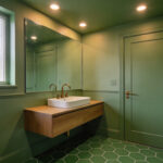 A small bathroom featuring color drenching with walls and ceiling painted in a uniform sage green to reduce spatial anxiety.